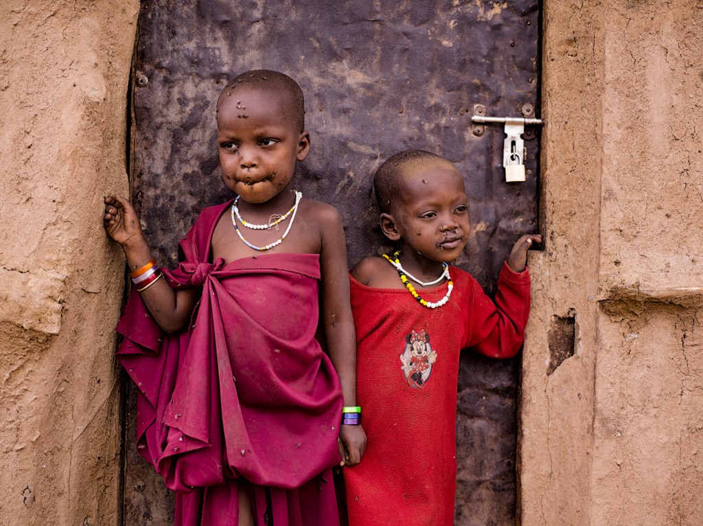 Friendly Maasai children standing in front of their Boma house in a village An image of friendly Maasai kids standing outside their Bomo home in a village in Tanzania taken with a Phase One IQ260